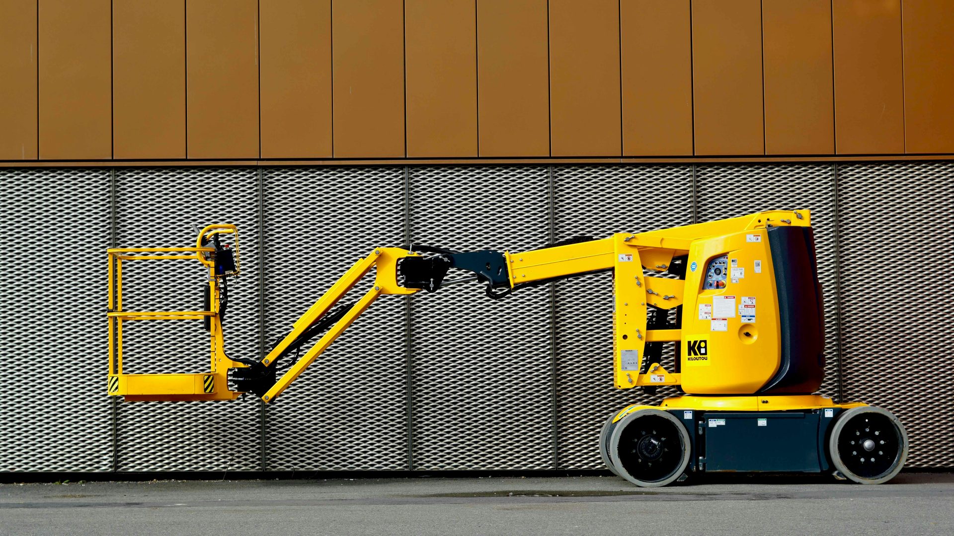 Vertical mast lift against industrial wall
